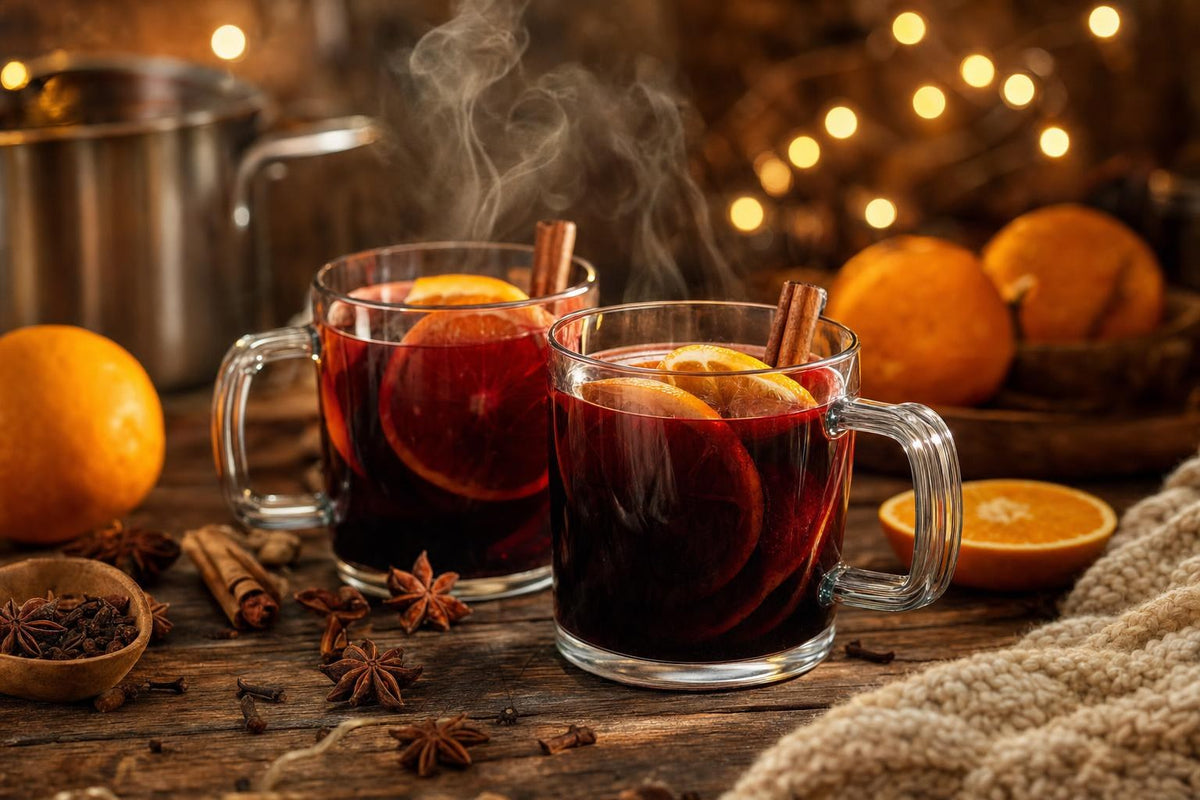 Dampfender Glühwein in Glastassen mit Orangenscheiben, Zimtstangen und Sternanis auf einem Holztisch